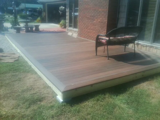 New wood deck and wicker chair beside a brick house in Clayton