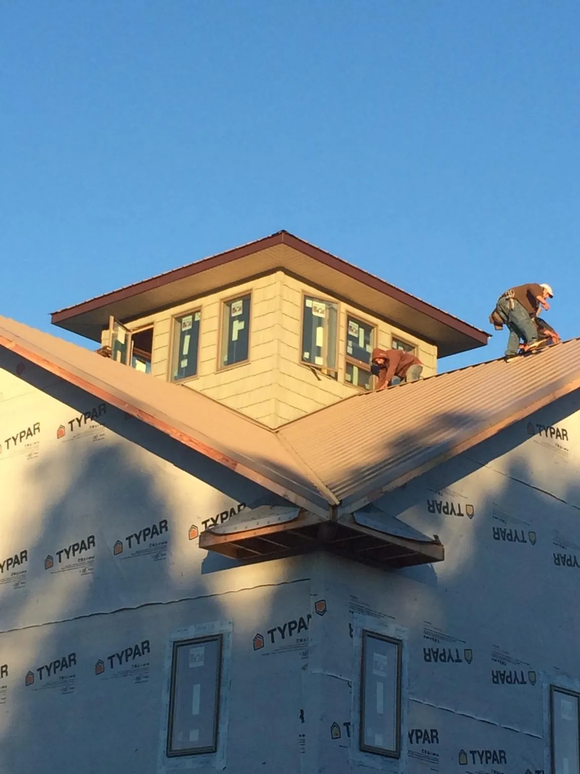 Roofers working around a rooftop cupola on a new metal roof at sunset — Roof Waterproofing in Clayton by Roofing Brothers